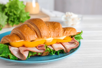 Photo of Tasty croissant sandwich with ham on white wooden table, closeup