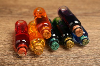 Bottles with different food coloring on wooden background, closeup