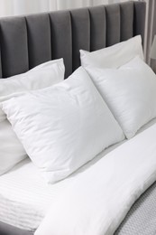 Soft white pillows and duvet on bed, closeup