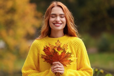 Portrait of happy woman with autumn leaves outdoors