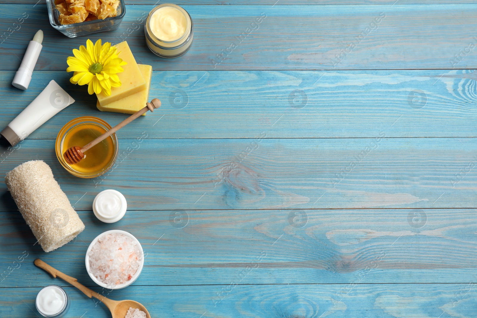 Photo of Flat lay composition with beeswax and cosmetic products on blue wooden table. Space for text