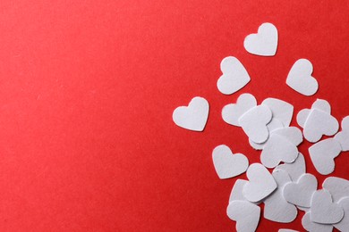 Photo of White paper hearts on red background, flat lay. Space for text