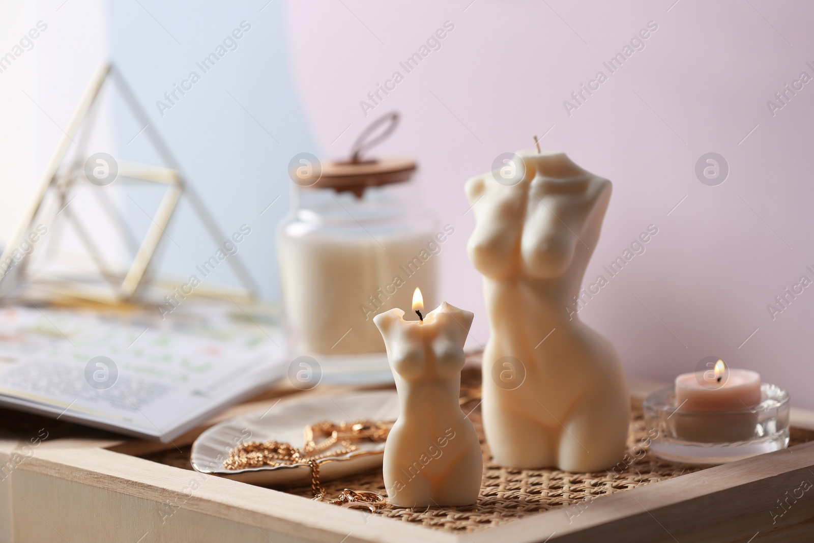 Photo of Beautiful body shaped candles and jewelry on tray indoors