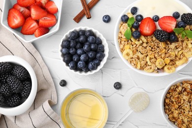 Photo of Tasty oatmeal, honey, yogurt and fresh berries served on white textured table, flat lay. Healthy breakfast