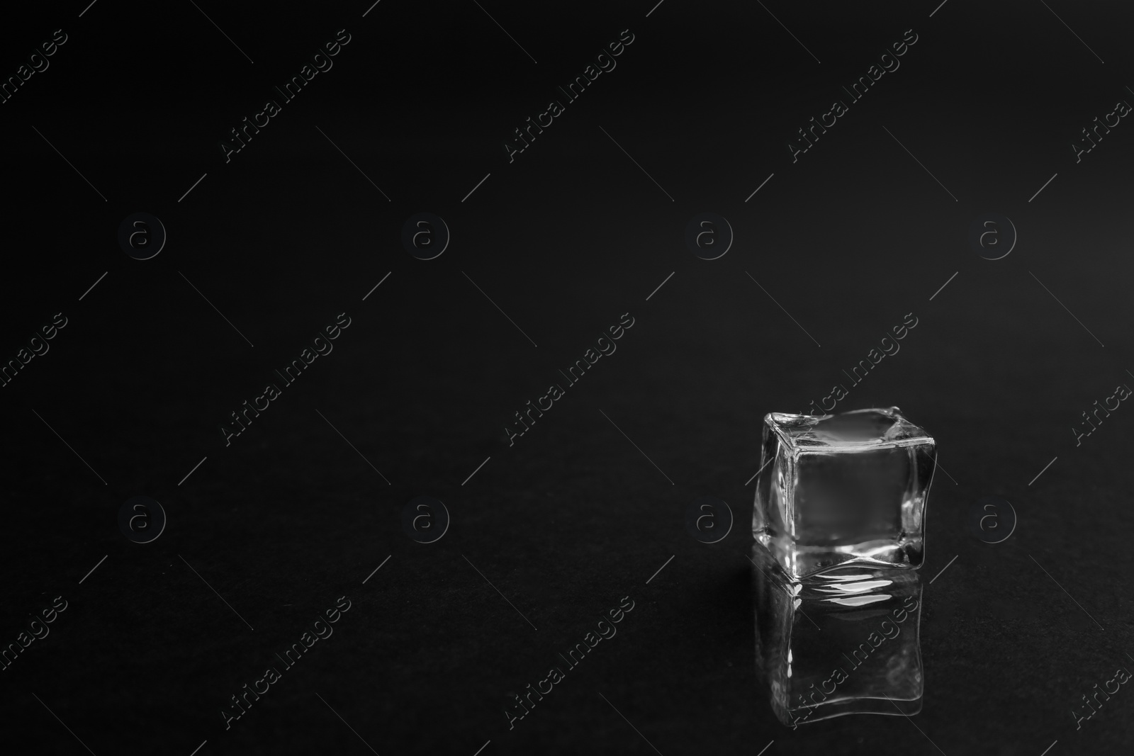 Photo of Crystal clear ice cube on black background. Space for text