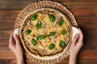 Woman holding tray with delicious homemade pizza on wooden background