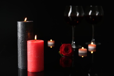 Photo of Burning candles and glasses with wine in darkness