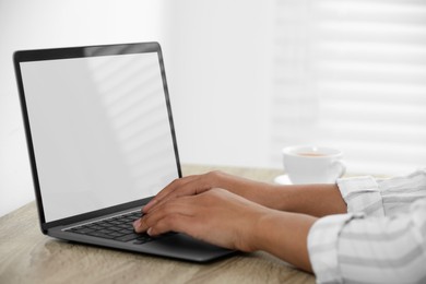 Woman using laptop at wooden desk indoors, closeup