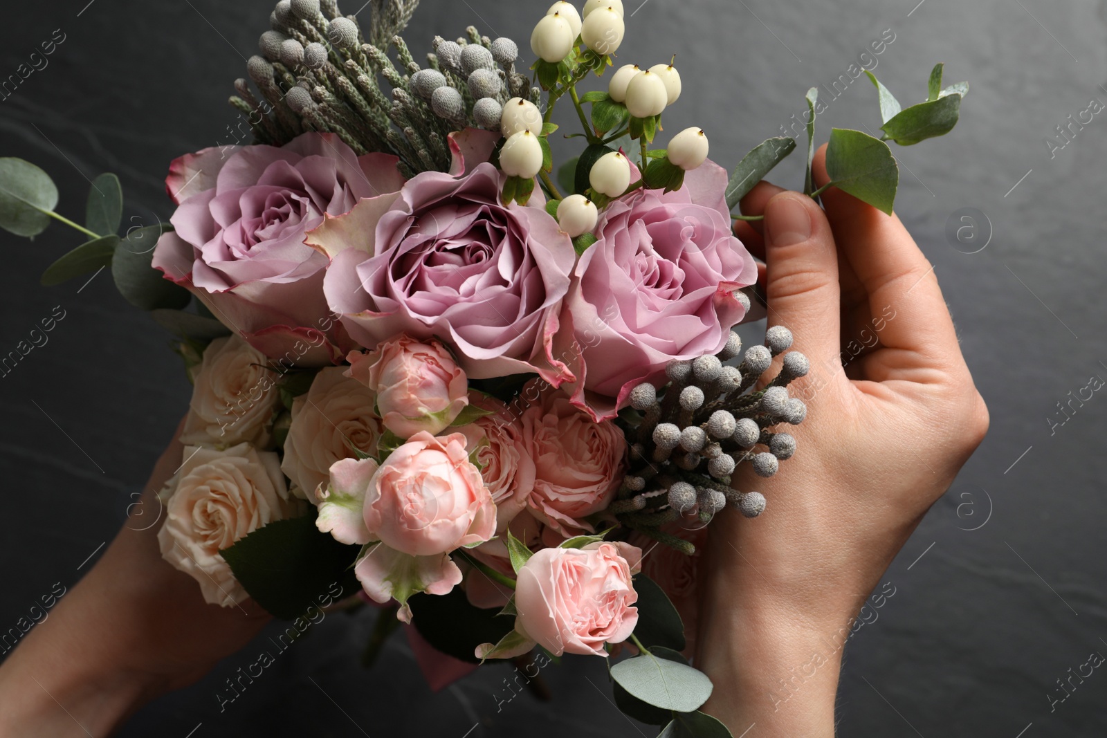 Photo of Florist creating beautiful bouquet at black table, top view