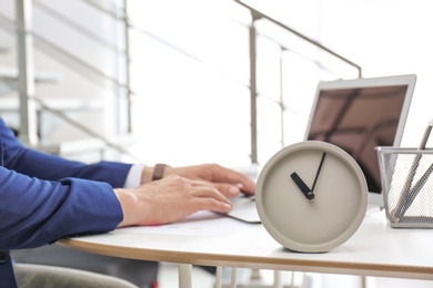 Photo of Clock and blurred man working on background. Time management