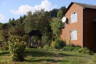 Modern house and swing near forest on sunny day