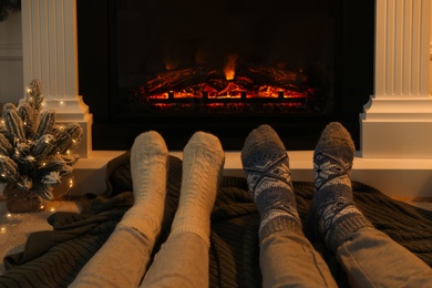 Couple in warm socks resting near fireplace at home, closeup