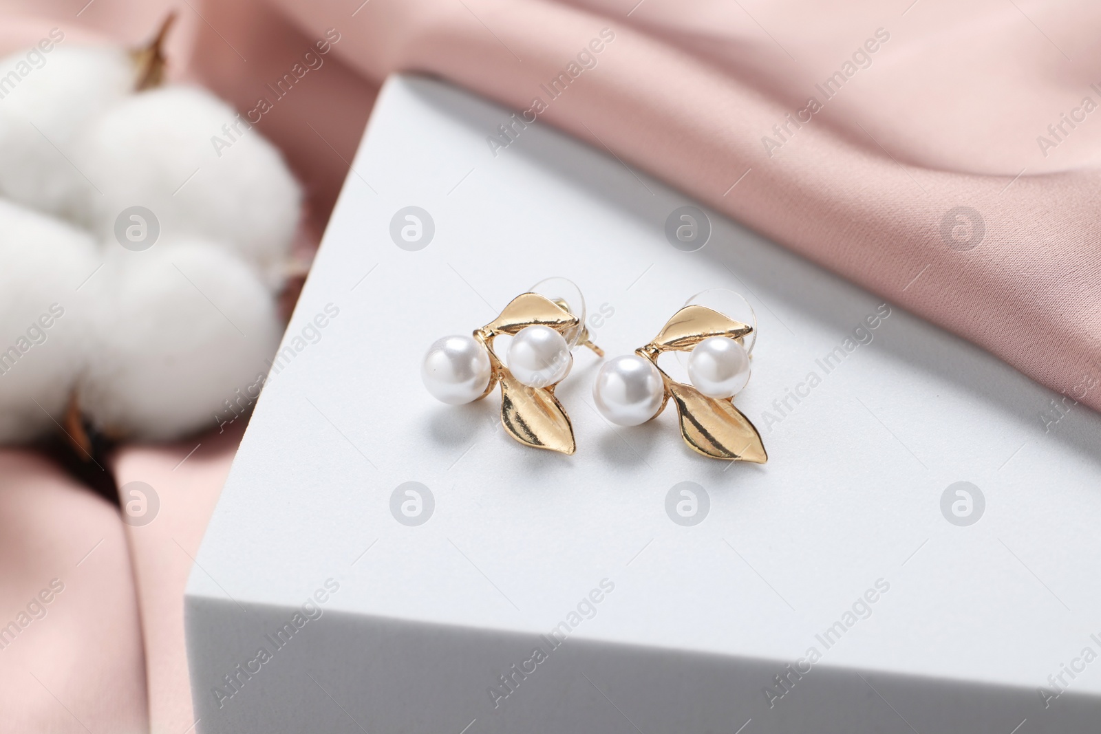 Photo of Beautiful earrings on white podium. Luxury jewelry