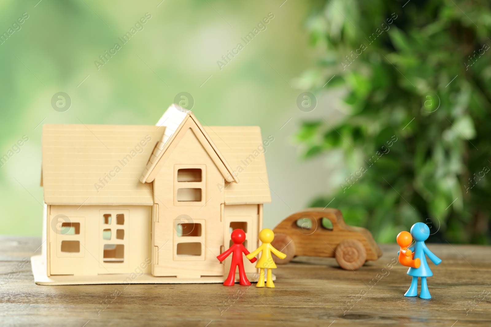 Photo of MYKOLAIV, UKRAINE - JANUARY 04, 2022: Colorful human figures, house model and toy car on wooden table. Surrogacy concept