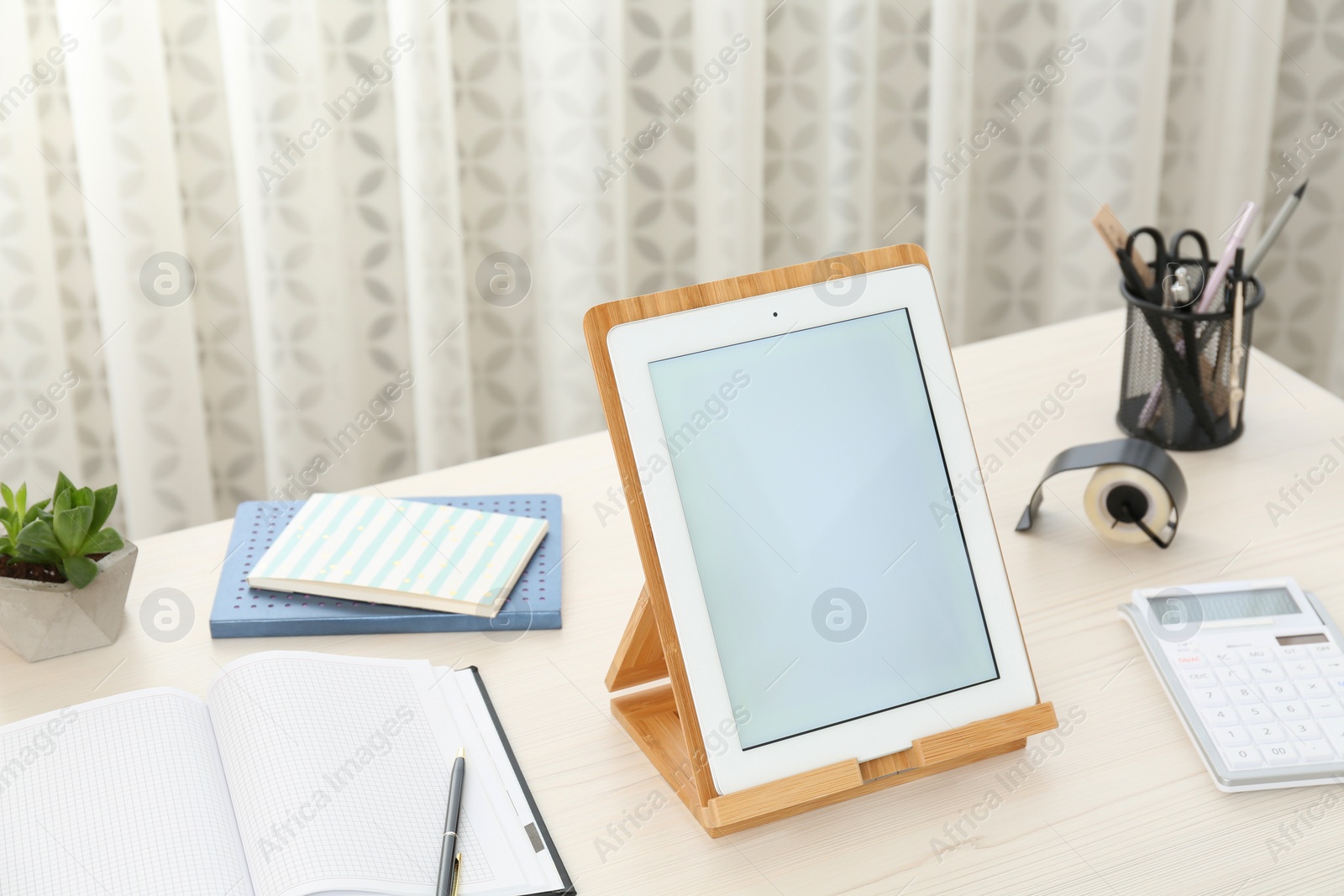 Photo of Modern tablet and stationery on wooden table indoors. Space for design