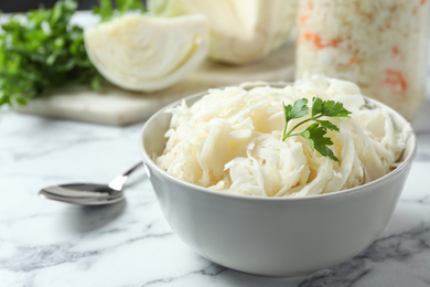 Photo of Tasty fermented cabbage on white marble table, closeup