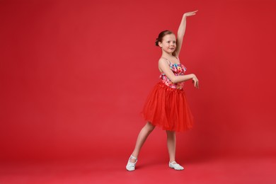 Cute little girl dancing on red background, space for text