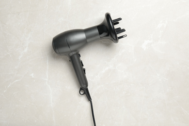 Photo of Hair dryer on light marble table, top view. Professional hairdresser tool