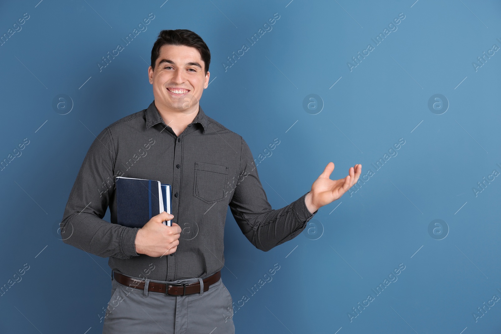 Photo of Portrait of male teacher with notebooks on color background