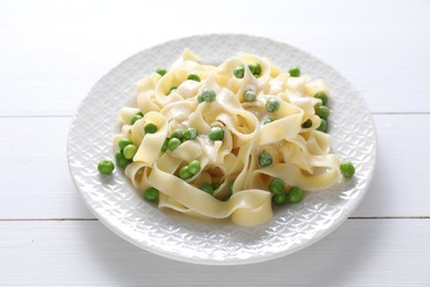 Delicious pasta with green peas on white wooden table