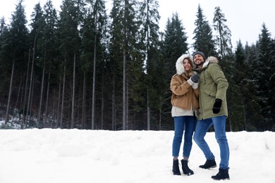 Photo of Couple near conifer forest on snowy day, space for text. Winter vacation
