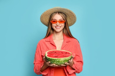 Photo of Beautiful girl with half of watermelon on light blue background