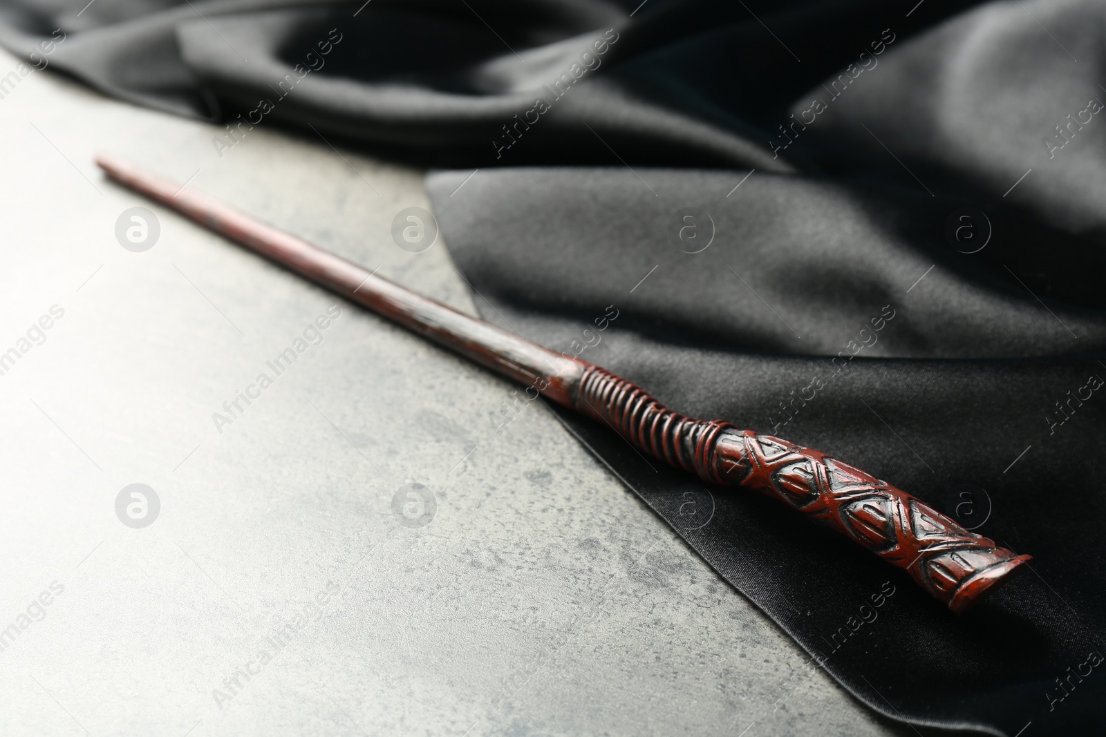 Photo of Magic wand and dark cloth on light grey table, closeup