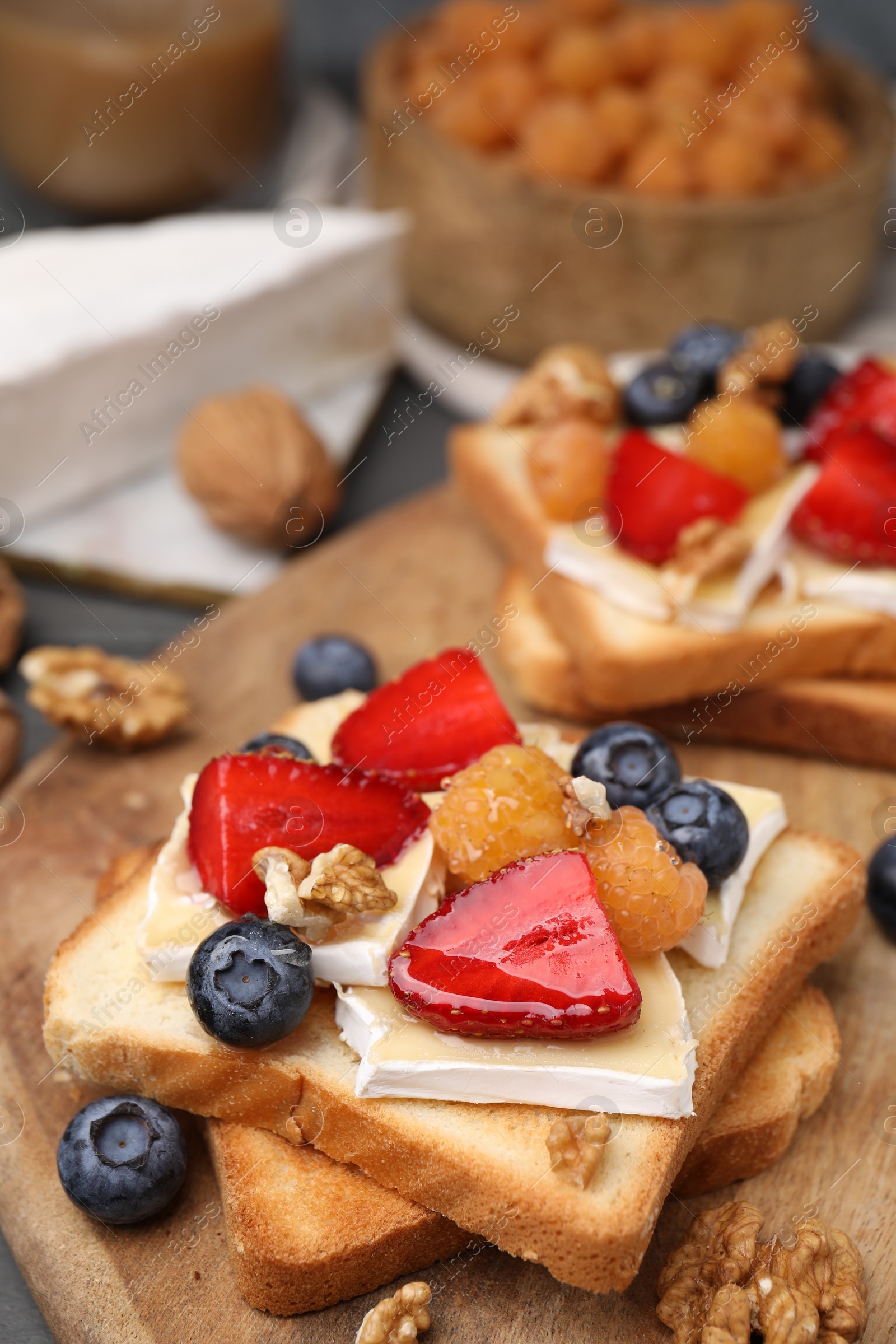 Photo of Tasty sandwiches with brie cheese, fresh berries and walnuts on table