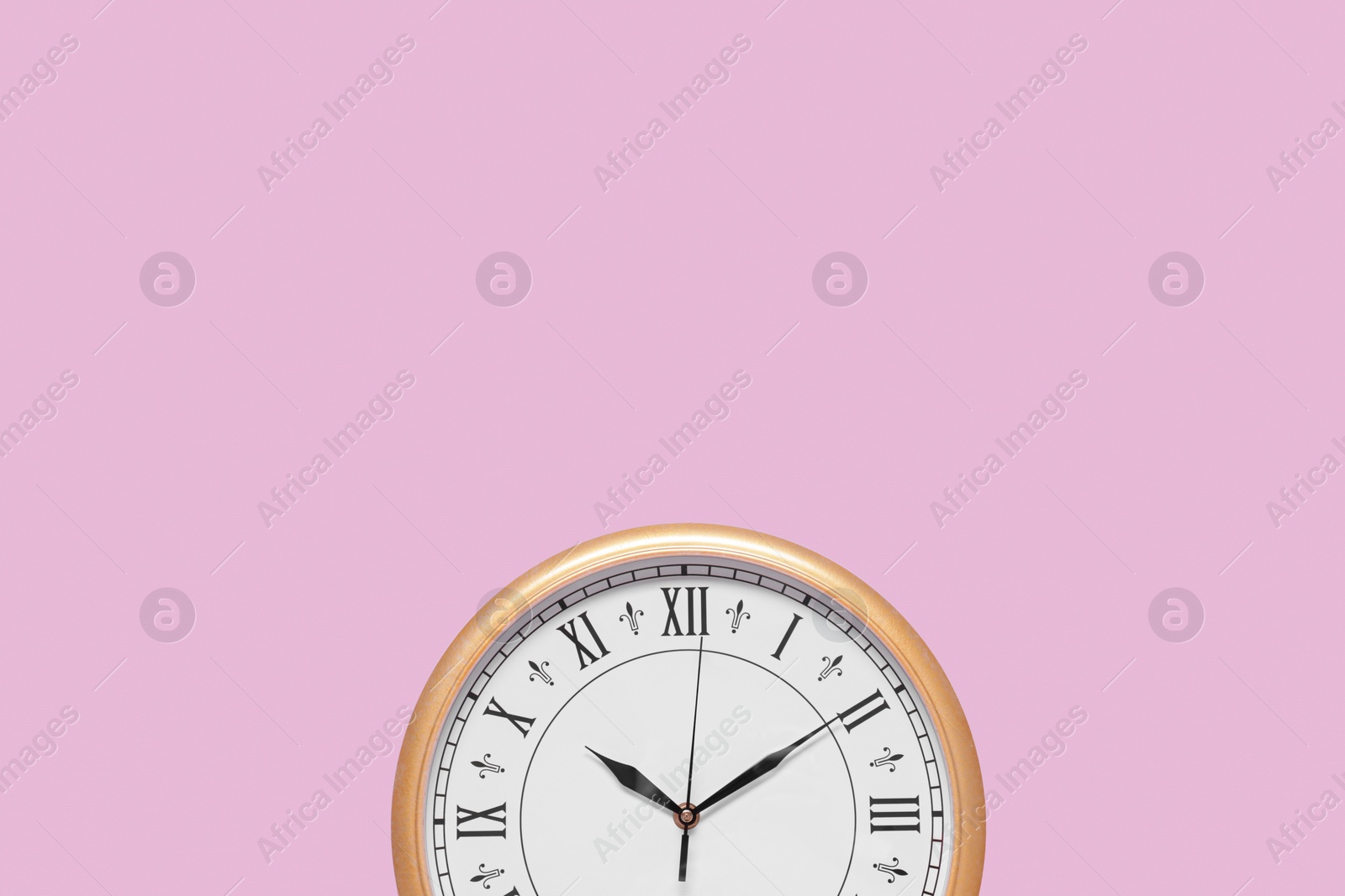 Photo of Stylish round clock on pale pink background, top view with space for text. Interior element