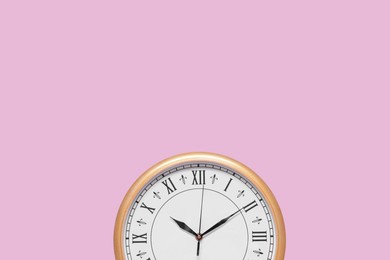 Stylish round clock on pale pink background, top view with space for text. Interior element