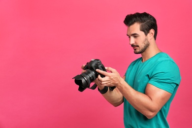 Photo of Young photographer with professional camera on pink background. Space for text