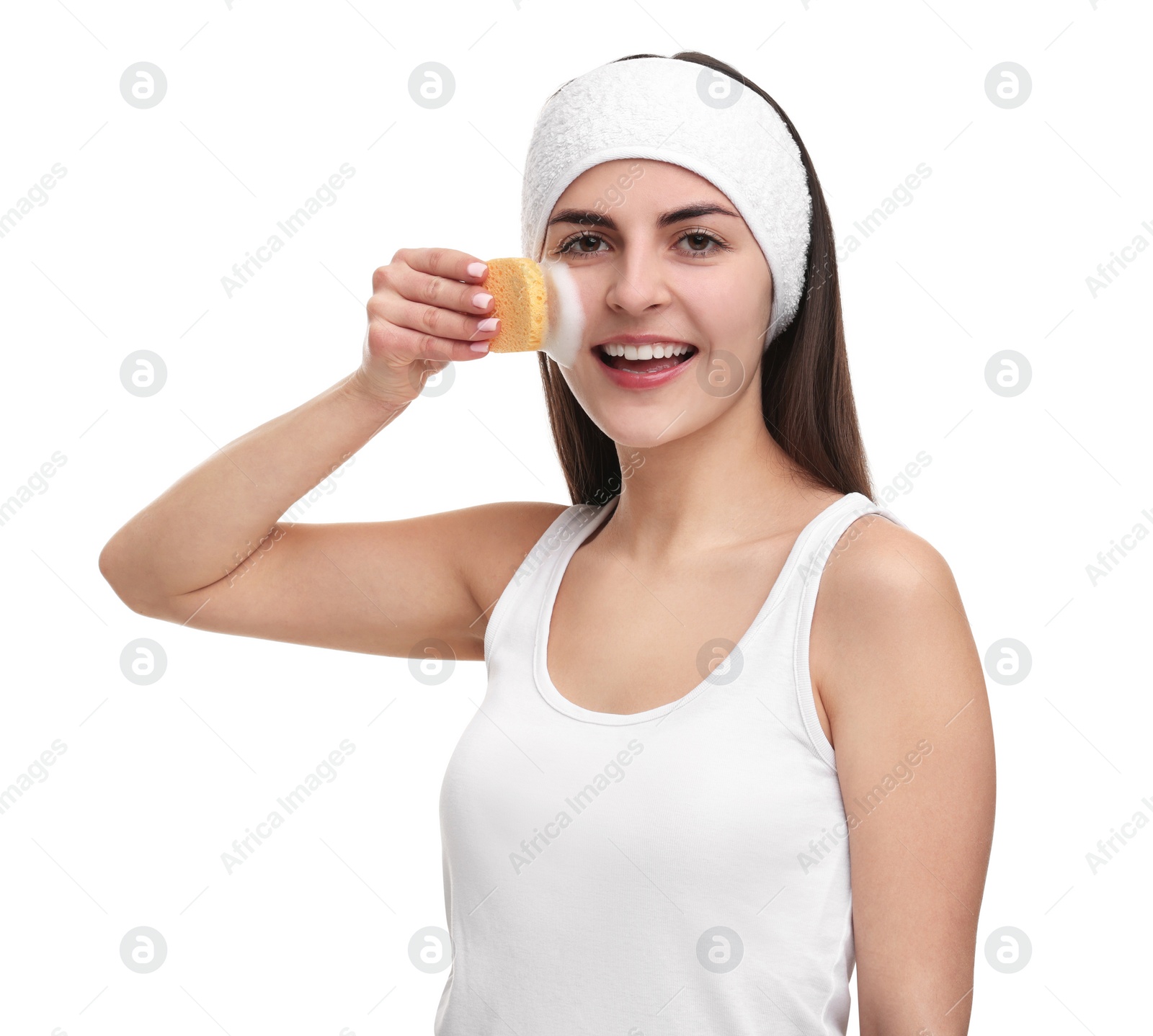 Photo of Young woman with headband washing her face using sponge on white background