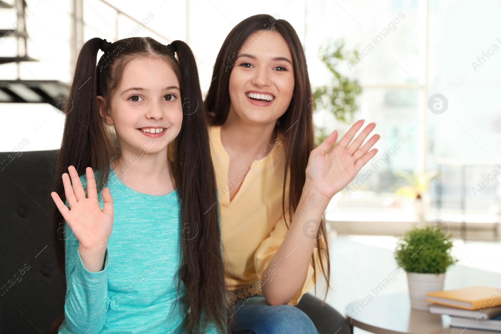 Photo of Mother and daughter using video chat at home, view from camera perspective