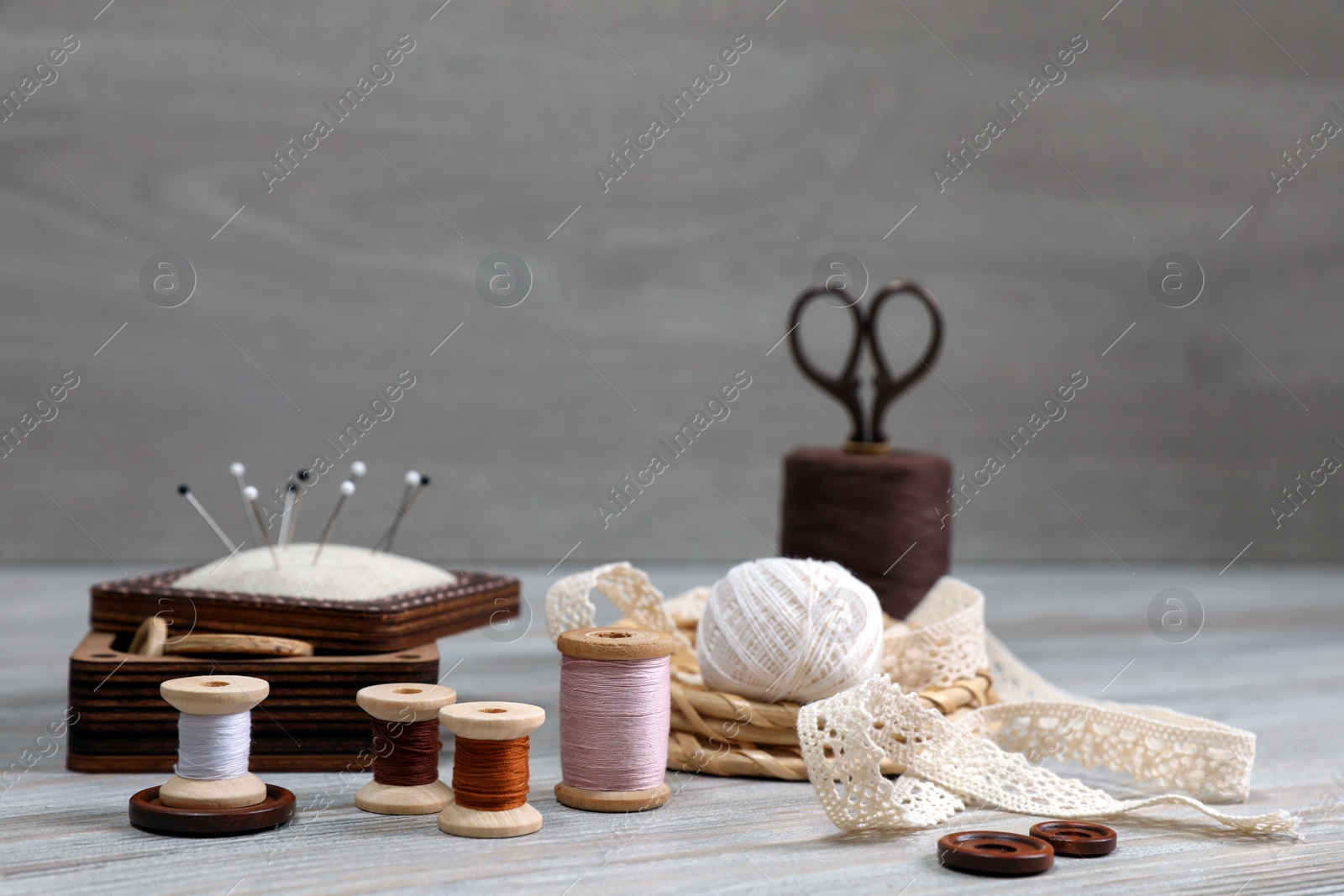 Photo of Color threads and different sewing accessories on white wooden table