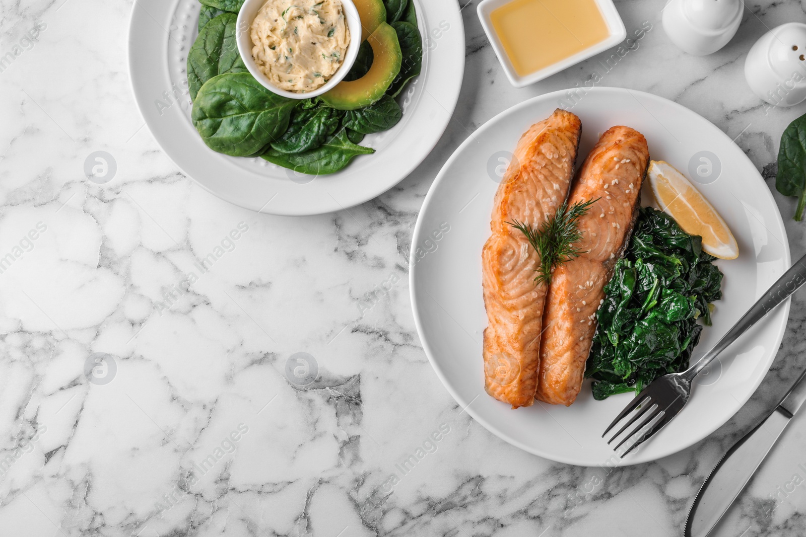 Photo of Tasty salmon with spinach and lemon served on marble table, flat lay. Space for text