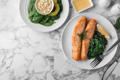 Photo of Tasty salmon with spinach and lemon served on marble table, flat lay. Space for text