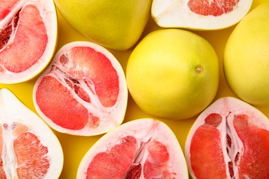 Tasty whole and cut pomelo fruits on yellow background, flat lay