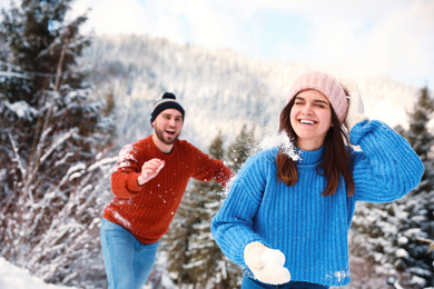 Photo of Happy couple playing snowballs outdoors. Winter vacation