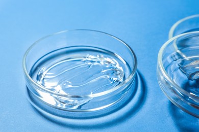 Photo of Petri dishes with liquids on blue background, closeup