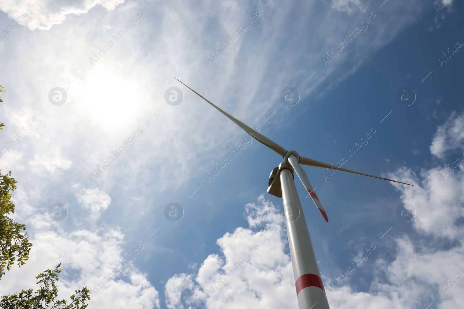 Photo of Modern wind turbine against cloudy sky, low angle view. Alternative energy source