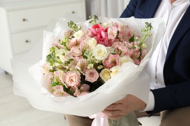 Photo of Man with beautiful bouquet of flowers indoors, closeup