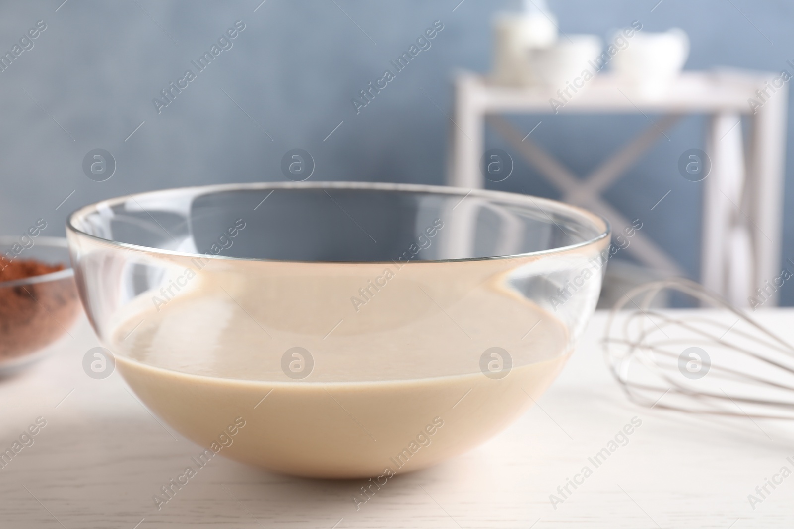 Photo of Glass bowl with batter on white table in kitchen