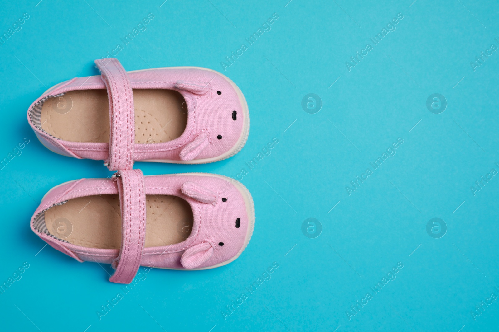 Photo of Cute baby shoes on light blue background, flat lay. Space for text