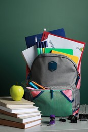 Photo of Backpack with different school stationery on white table near chalkboard