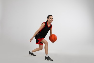 Photo of Professional sportswoman playing basketball on grey background