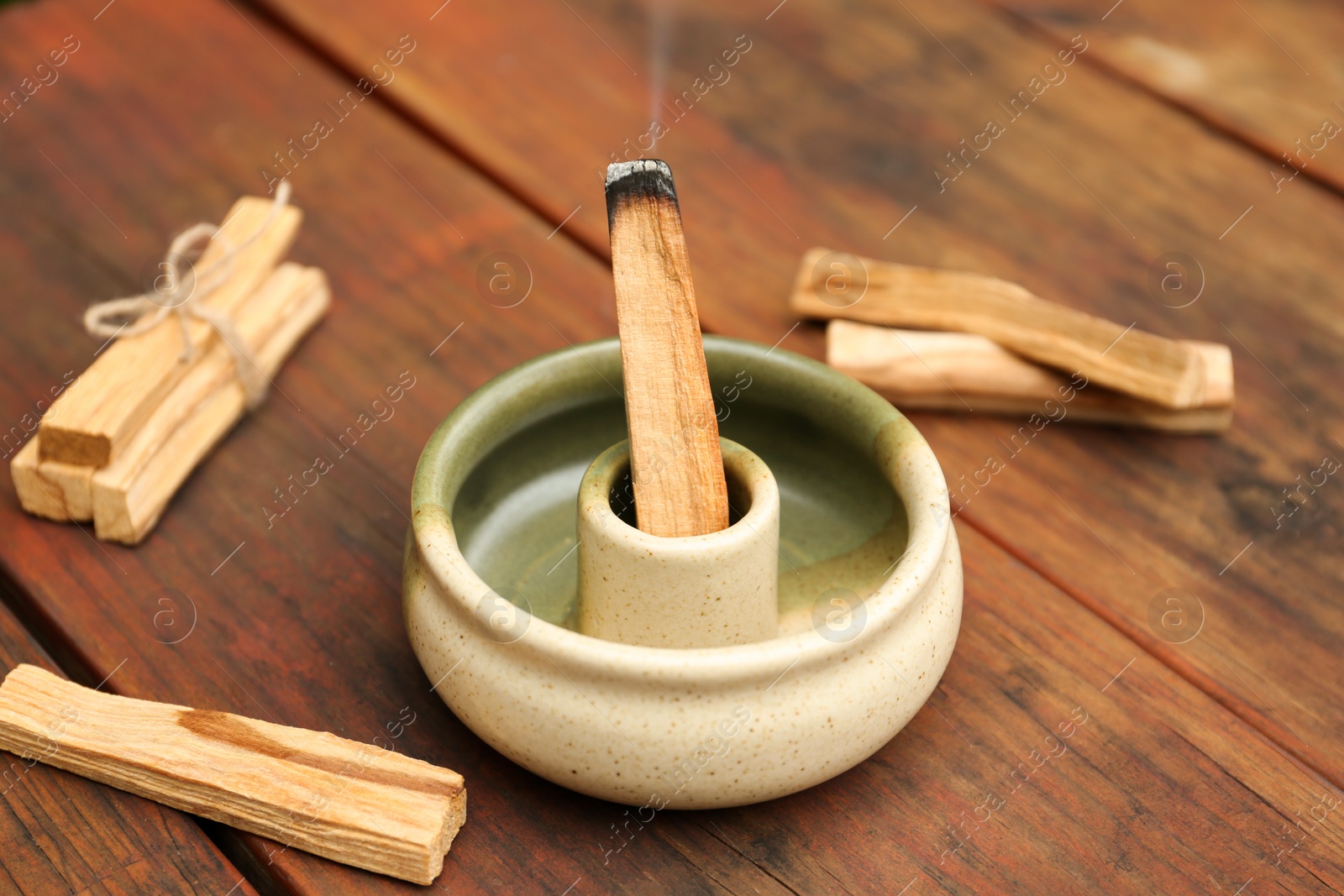 Photo of Palo Santo stick smoldering in holder on wooden table