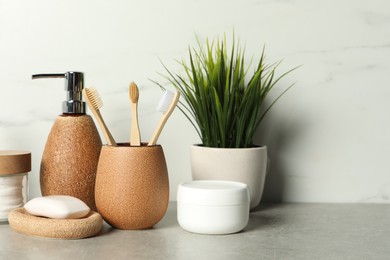 Photo of Different bath accessories and personal care products on gray table near white marble wall