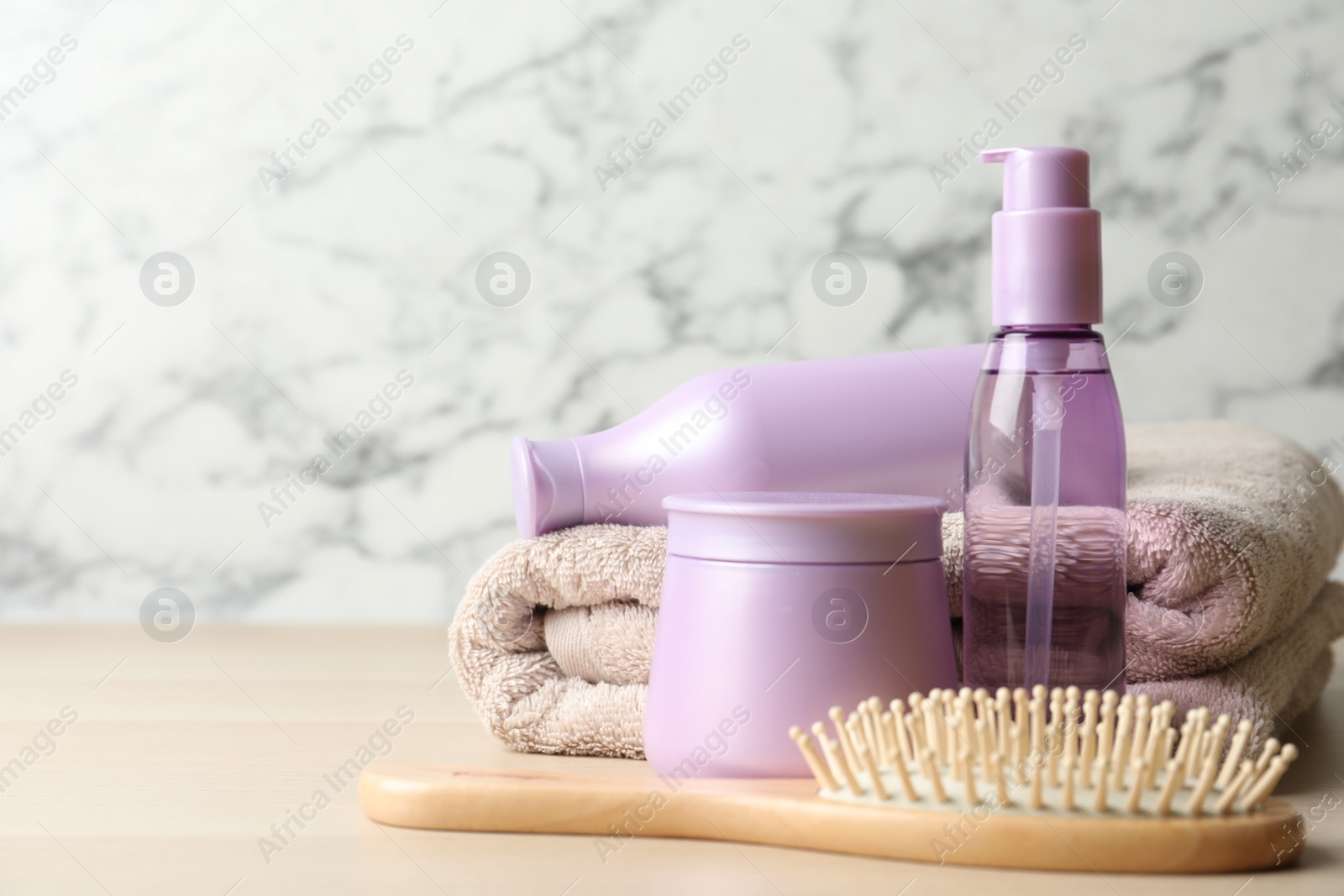 Photo of Different hair care products, towel and brush on wooden table. Space for text