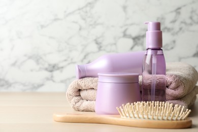 Different hair care products, towel and brush on wooden table. Space for text