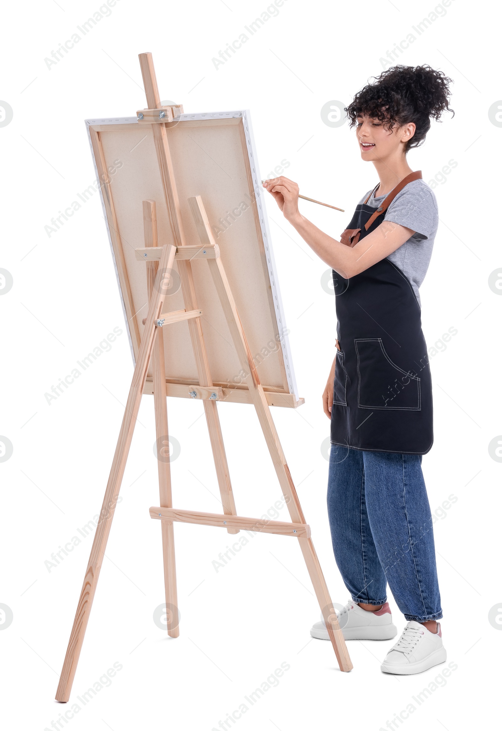 Photo of Young woman painting on easel with canvas against white background